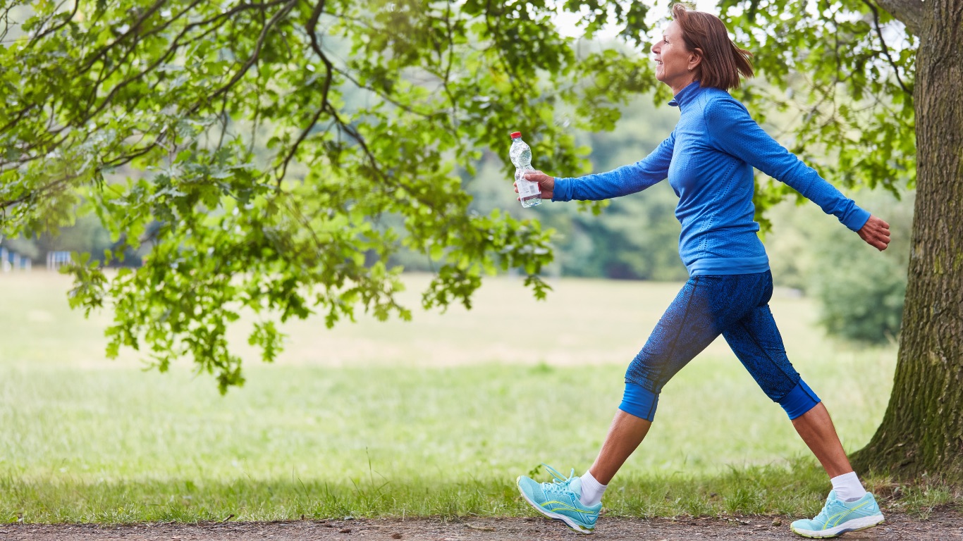 A woman walking outside with water after exercise